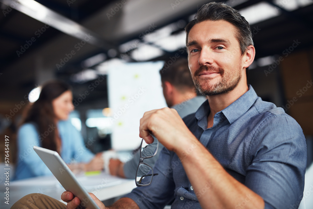 Poster the creative process. portrait of a man sitting at a table in an office using a digital tablet with 
