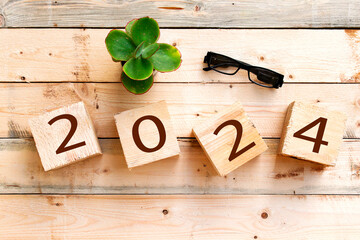 2024 new year greeting card template, 2023 on wooden cubes on wood table, aloe vera pot and eyeglasses 
