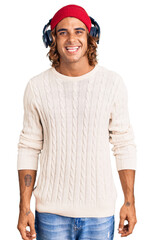 Young hispanic man listening to music using headphones with a happy and cool smile on face. lucky person.