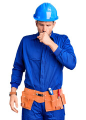 Young handsome man wearing worker uniform and hardhat with hand on stomach because indigestion, painful illness feeling unwell. ache concept.