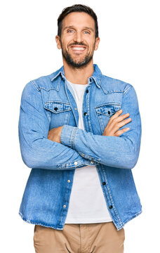 Young handsome man wearing casual denim jacket happy face smiling with crossed arms looking at the camera. positive person.