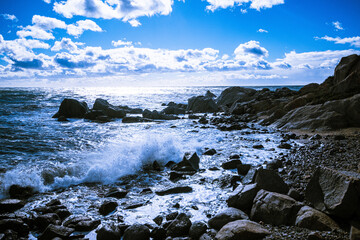 Waves of the Mediterranean Sea which with foam and splashes break against huge stones on the shore, Cagliari, Sardinia, Italy