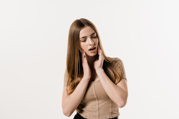 Toothache of young woman on white background. Girl is touching cheek and feeling teeth hurt on white background. Tooth decay, infection or injury to the tooth or gums.