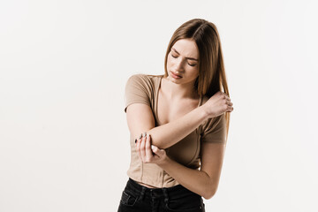 Elbow injury of girl on white background. Traumatology. Attractive girl with pain and bruise in her arm due to an accident. - obrazy, fototapety, plakaty