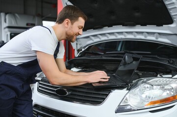 car mechanic using a computer laptop to diagnosing and checking up on car engines parts for fixing and repair