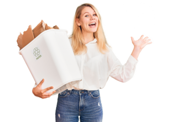 Young beautiful blonde woman holding recycle paper bin celebrating victory with happy smile and winner expression with raised hands