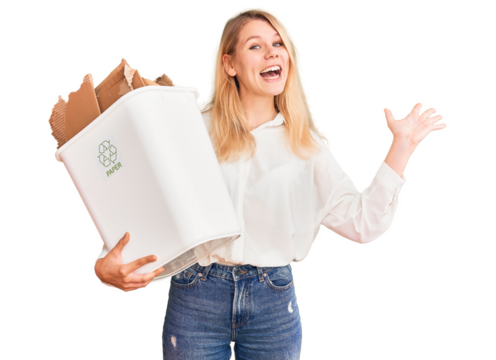 Young beautiful blonde woman holding recycle paper bin celebrating victory with happy smile and winner expression with raised hands - Powered by Adobe