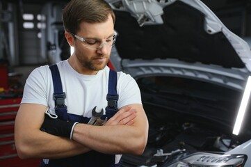 Fototapeta na wymiar Muscular car service worker repairing vehicle.