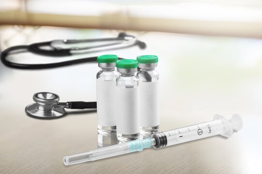 Bottles of medical vaccine vials with stethoscope on desk