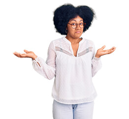 Young african american girl wearing casual clothes clueless and confused expression with arms and...