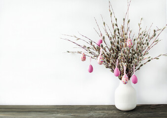 Spring, Easter holiday.  Minimalistic style white vase with willow branches and Easter eggs on a light background.  The concept of ecological, natural style.  Space for copy text.