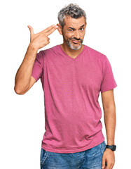 Middle age grey-haired man wearing casual clothes shooting and killing oneself pointing hand and fingers to head like gun, suicide gesture.