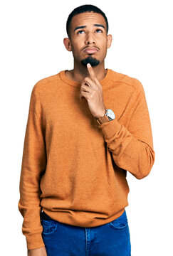 Young african american man wearing casual clothes thinking concentrated about doubt with finger on chin and looking up wondering