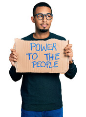 Young african american man holding power to the people banner smiling looking to the side and staring away thinking.
