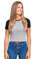 Fototapeta premium Young blonde woman wearing casual clothes looking away to side with smile on face, natural expression. laughing confident.