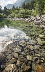 Mountain landscape and reflection in a mountain lake of a rocky mountain and forest, a mountain transparent lake in a sunny summer in the mountains