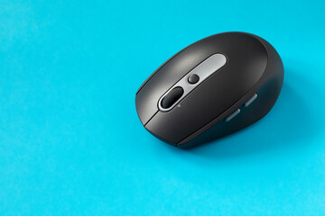 Black computer mouse on blue background. Wireless optical PC mouse. Wireless technology