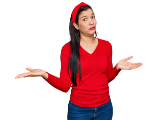 Young hispanic woman wearing casual clothes clueless and confused expression with arms and hands...