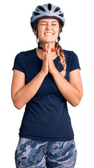 Beautiful caucasian woman wearing bike helmet praying with hands together asking for forgiveness smiling confident.