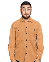 Young hispanic man wearing casual clothes puffing cheeks with funny face. mouth inflated with air, crazy expression.