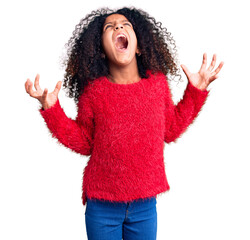 African american child with curly hair wearing casual winter sweater crazy and mad shouting and yelling with aggressive expression and arms raised. frustration concept.
