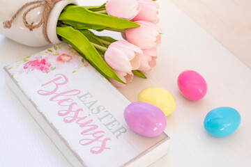 Easter background. Pink flowers tulips. bright colored eggs and a wooden sign with the inscription happy easter.
