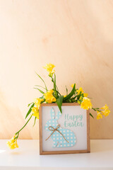 Wooden frame with the inscription happy easter and yellow flowers
