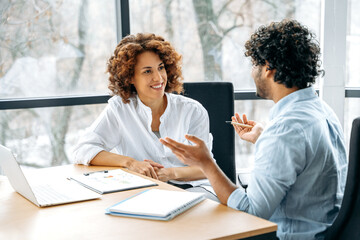 Two positive confident motivated employees of the company of different nationalities are working...