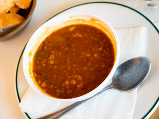 Tasty lentils stew with meat and sausages in white bowl, Potaje de lentejas