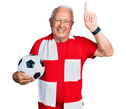 Senior man with grey hair football hooligan holding ball smiling amazed and surprised and pointing up with fingers and raised arms.