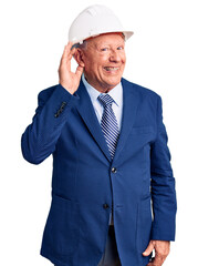Senior handsome grey-haired man wearing suit and architect hardhat smiling with hand over ear listening an hearing to rumor or gossip. deafness concept.