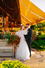 the bride and groom embrace on the terrace in the park near the restaurant.