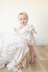 infant girl with limb disability standing in a vintage dress and bonnet