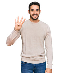 Young hispanic man wearing casual clothes showing and pointing up with fingers number four while smiling confident and happy.