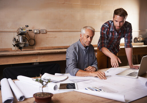 Passing along all his knowledge. Cropped shot of a father and son working together in their workshop.