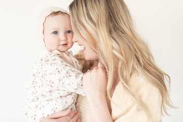 close up of mother and baby daughter with floral dress and bonnet
