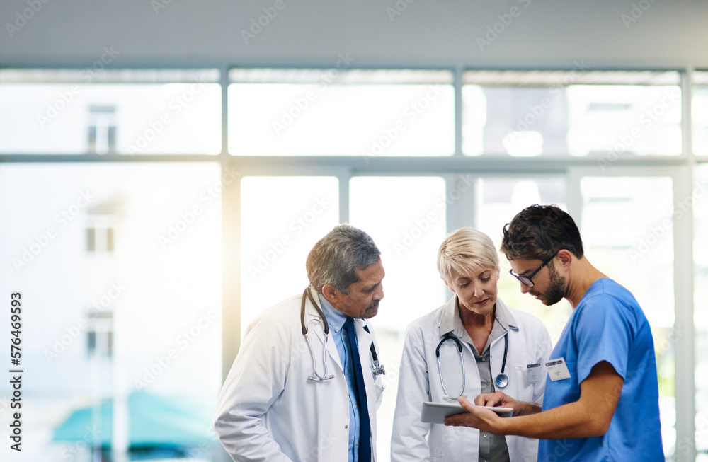 Poster Smart doctors use smart apps. Shot of a team of doctors using a digital tablet together in a hospital.