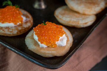 Tasty appetizer for dinner, small pancakes bliny with red fish caviar and sour cream