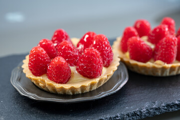 Artisanal baked small tart with cream and fresh ripe red raspberry