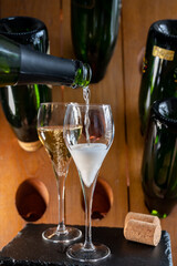 Glasses of sparkling white wine champagne or cava with bubbles and classic wooden champagne pupitre rack with empty bottles on background