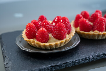 Artisanal baked small tart with cream and fresh ripe red raspberry