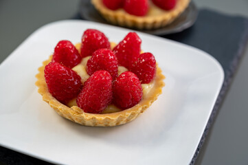 Artisanal baked small tart with cream and fresh ripe red raspberry