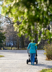Mother walking with a stroller in a park on a sunny day