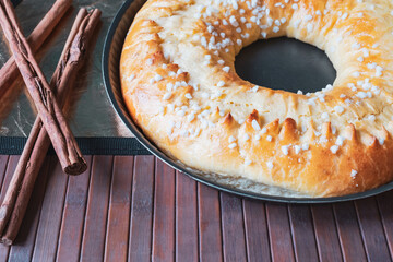 Close up of a delicious brioche with cinnamon sticks on a wooden background