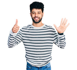Young arab man with beard wearing casual striped sweater showing and pointing up with fingers number six while smiling confident and happy.