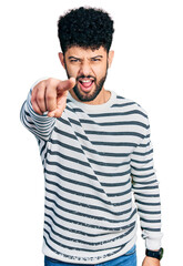 Young arab man with beard wearing casual striped sweater pointing displeased and frustrated to the camera, angry and furious with you