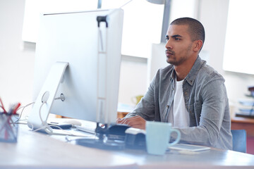 Youthful focus on professional solutions. Young creative man at work on his pc in a bright open office.