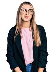 Hispanic young woman wearing business jacket and glasses smiling looking to the side and staring away thinking.