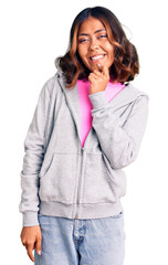 Young beautiful mixed race woman wearing casual sporty clothes looking confident at the camera with smile with crossed arms and hand raised on chin. thinking positive.