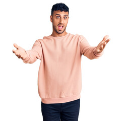 Young hispanic man wearing casual clothes smiling cheerful offering hands giving assistance and acceptance.